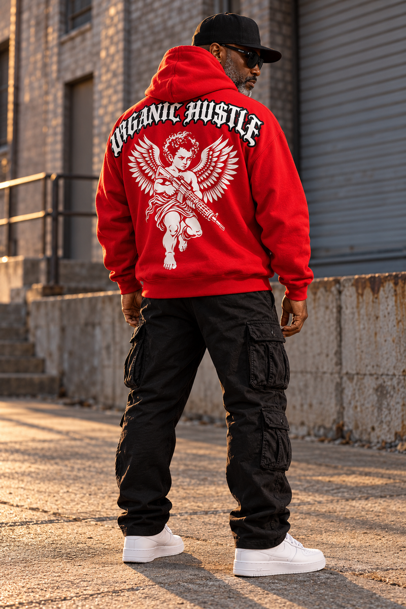 Outdoor styling mockup of the red Organic Hu$tle Guardian Angel hoodie worn with black cargo pants