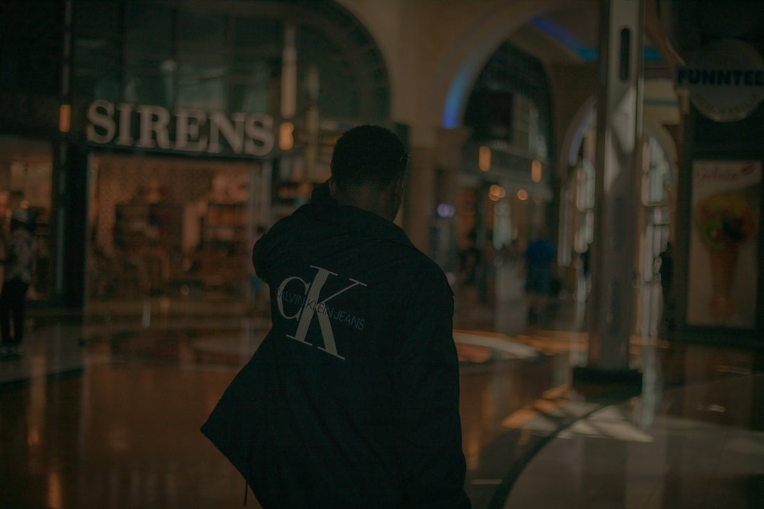 man in black hoodie standing in front of glass window