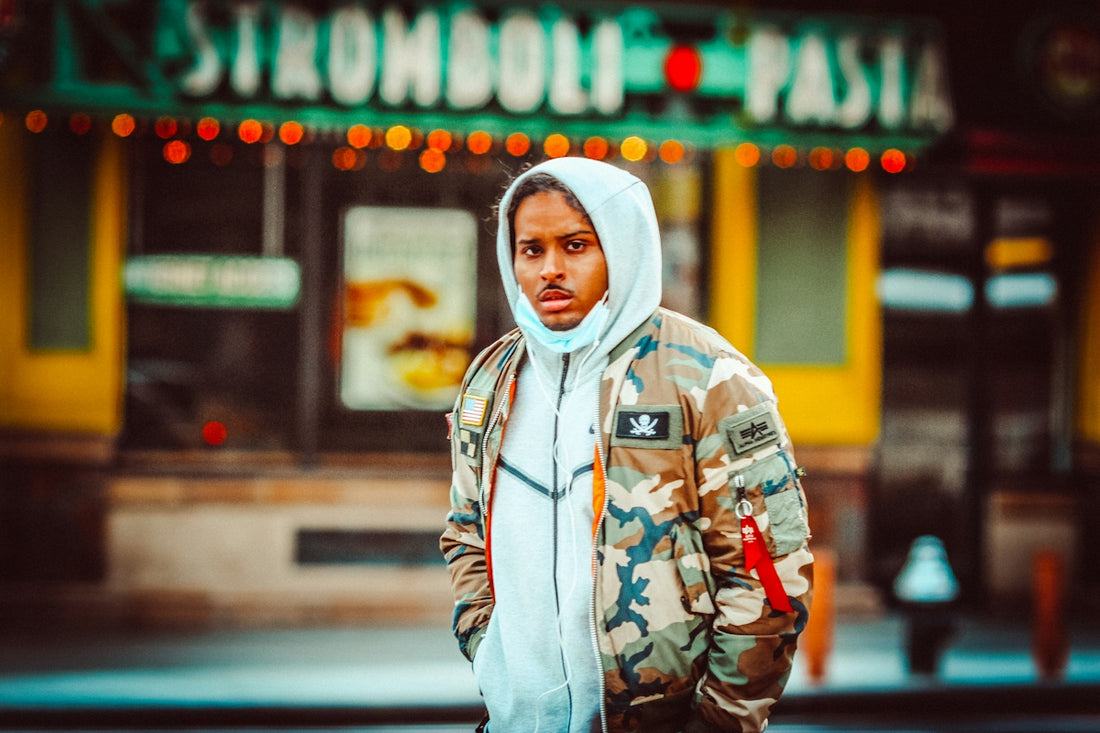 man in gray hoodie standing near store during daytime
