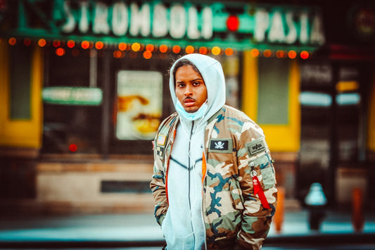 man in gray hoodie standing near store during daytime