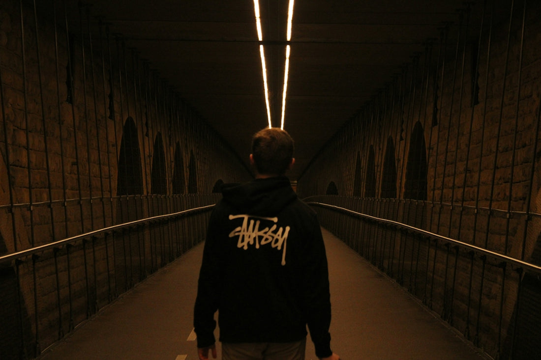 a man walking down a dark tunnel carrying a skateboard