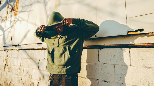 a man in a green hoodie leaning against a wall