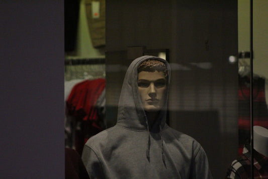 A mannequin wearing a hoodie in a store window