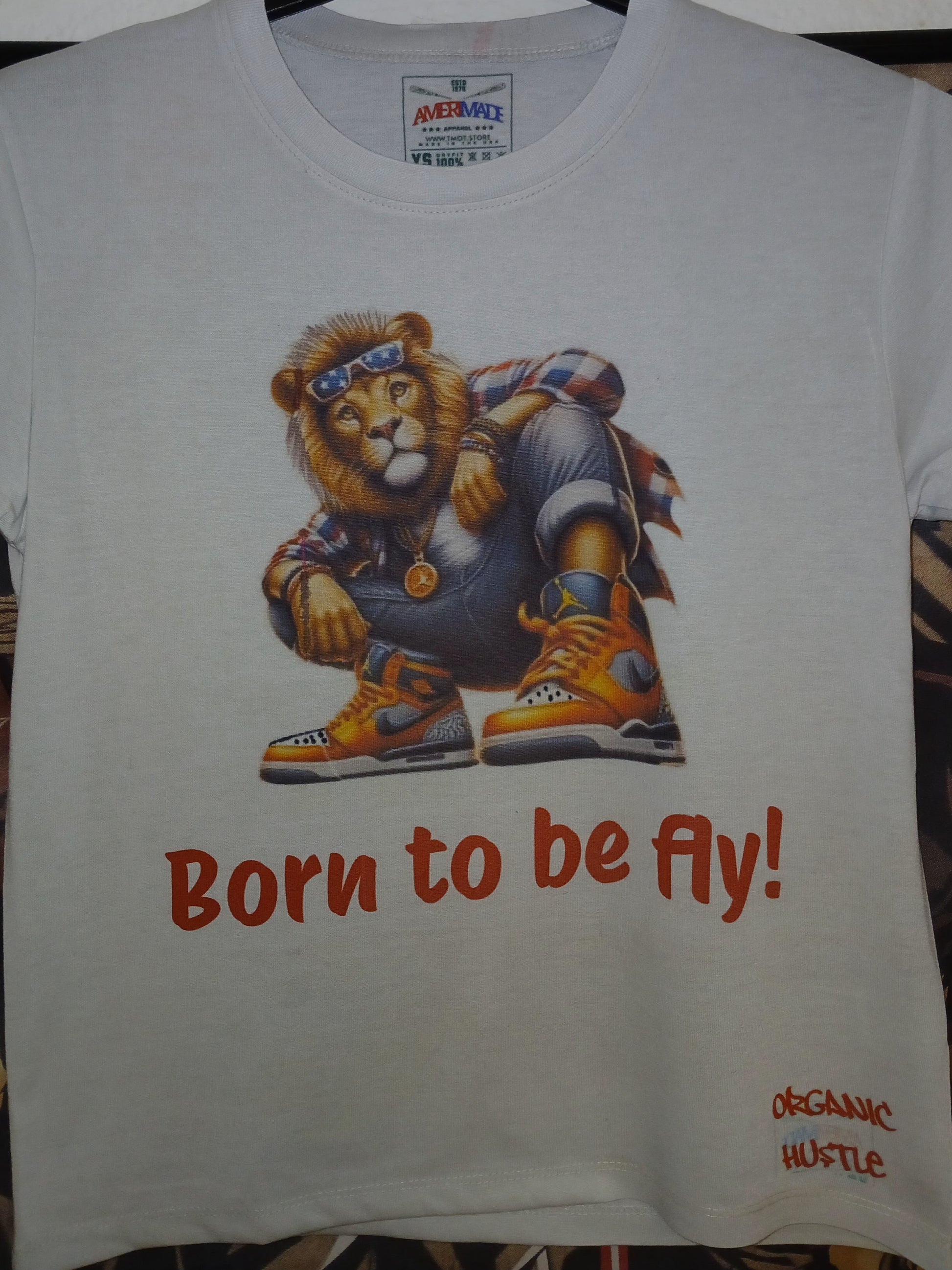 White t-shirt with a graphic of a lion and text 'Born to be fly!' on a plain background.