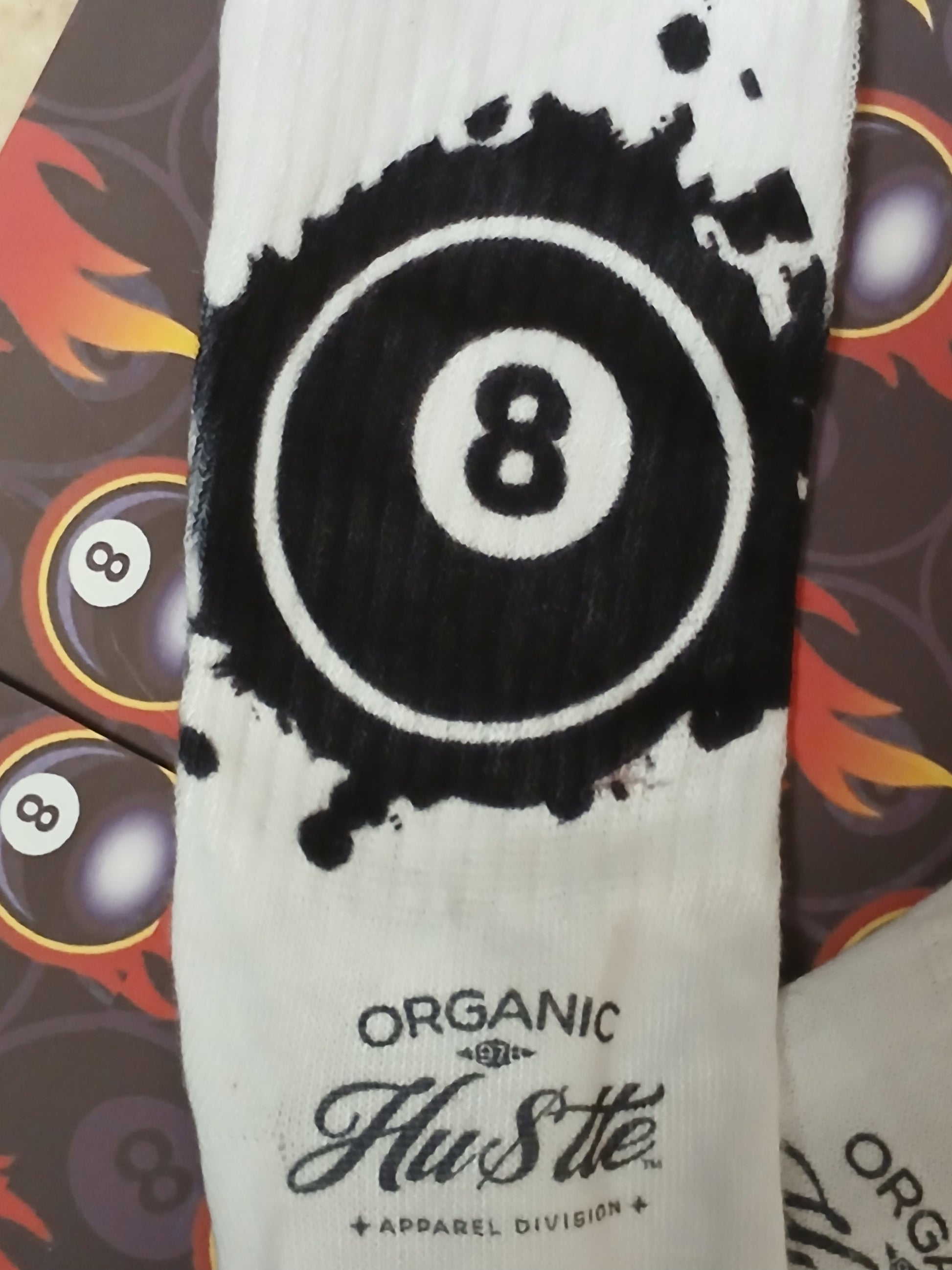 White sock with black number 8 design and 'Organic Hustle' branding on a patterned background.