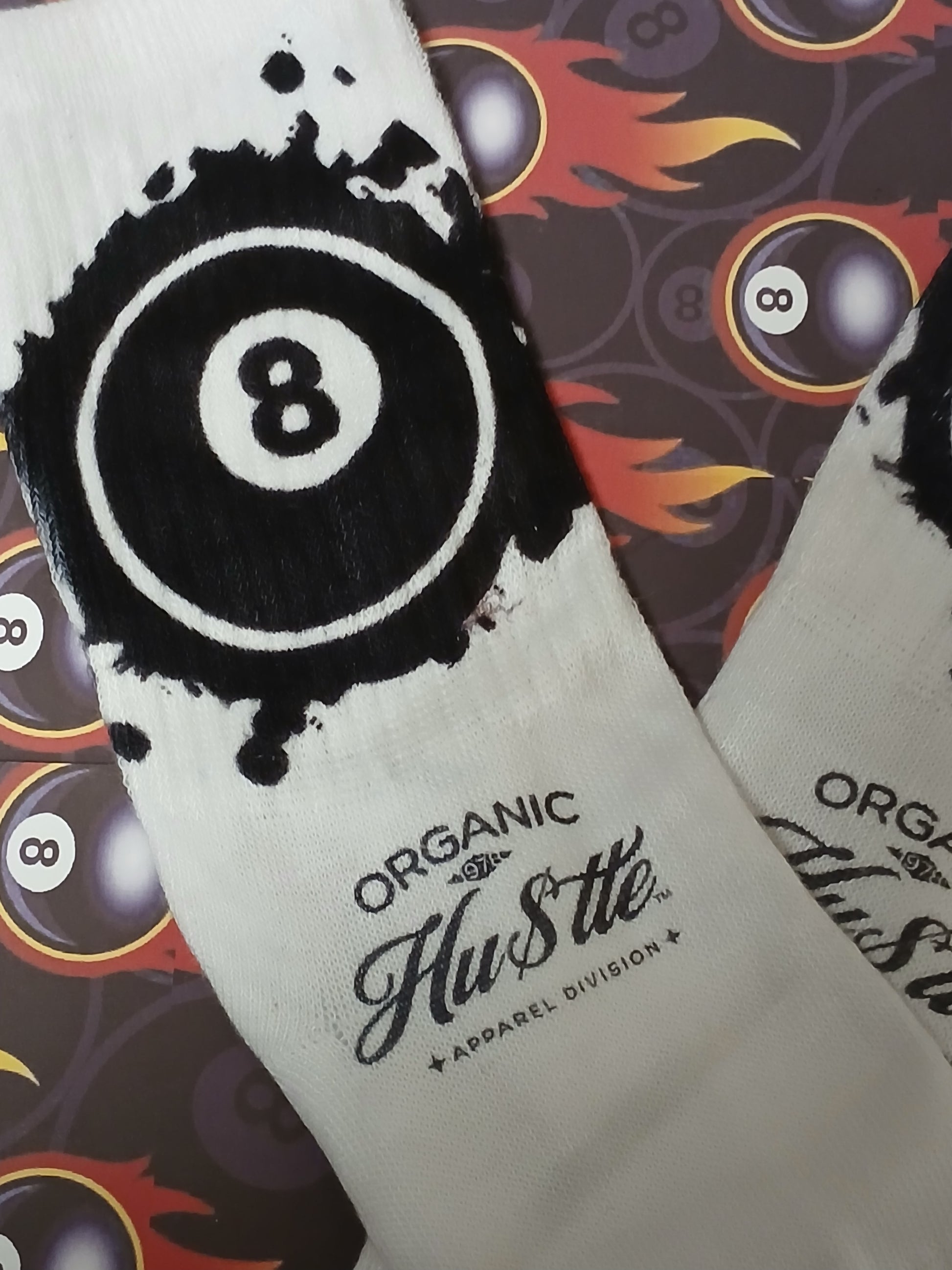 White socks with black '8' design and 'Organic Hustle' branding on a patterned background.