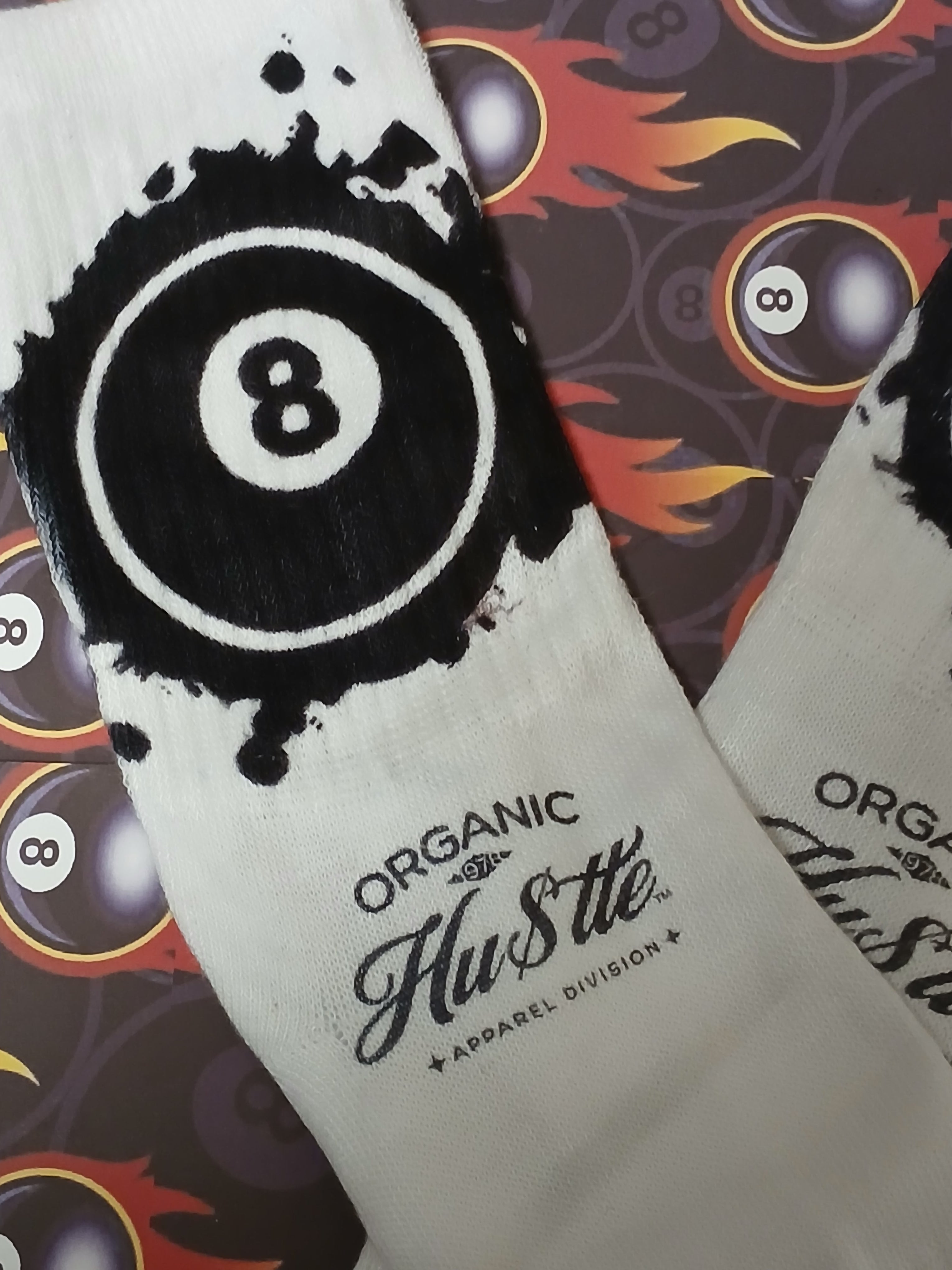 White socks with black '8' design and 'Organic Hustle' branding on a patterned background.