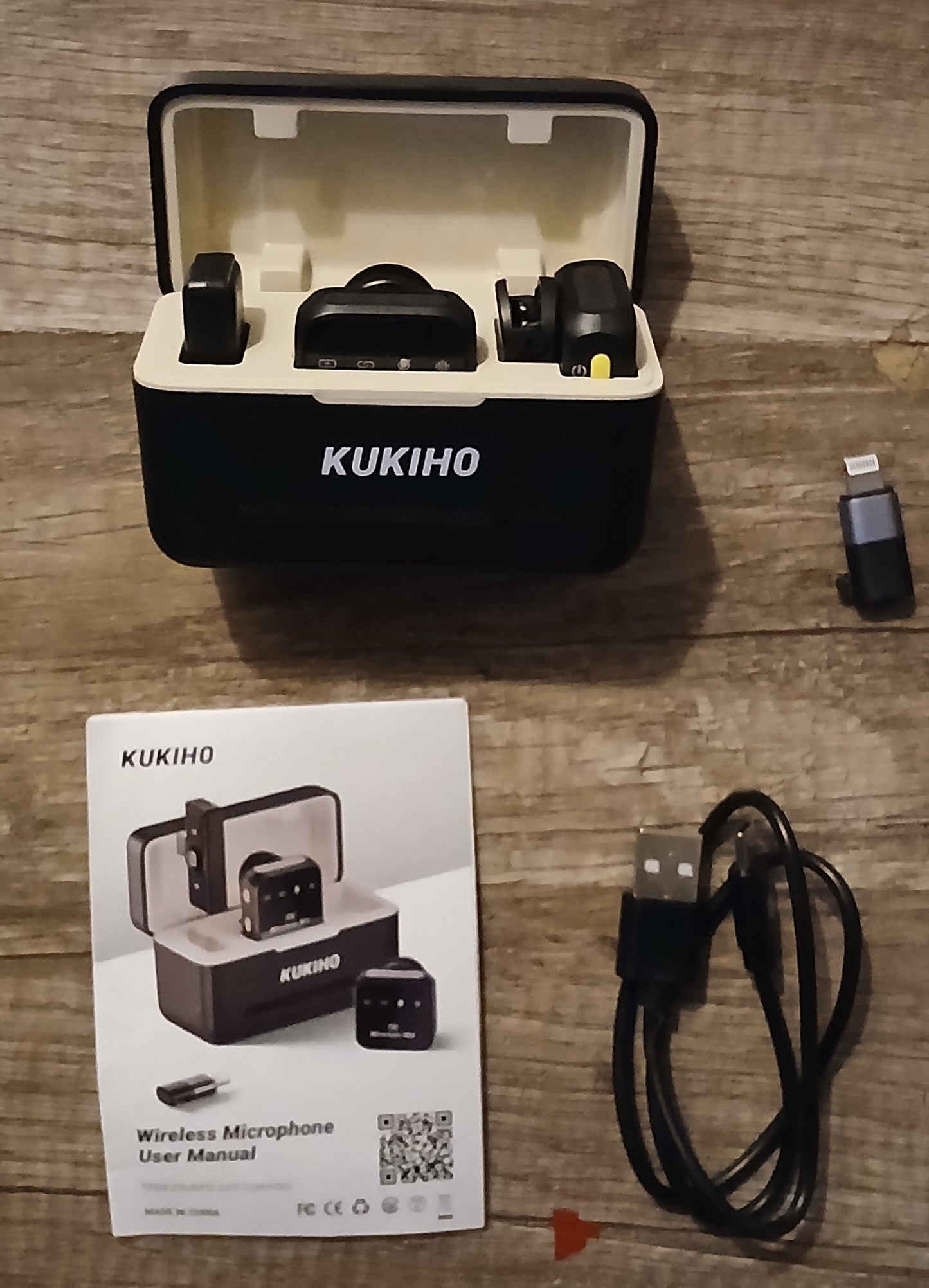 KUKIHO wireless microphone set with packaging, USB cable, and user manual on a wooden surface