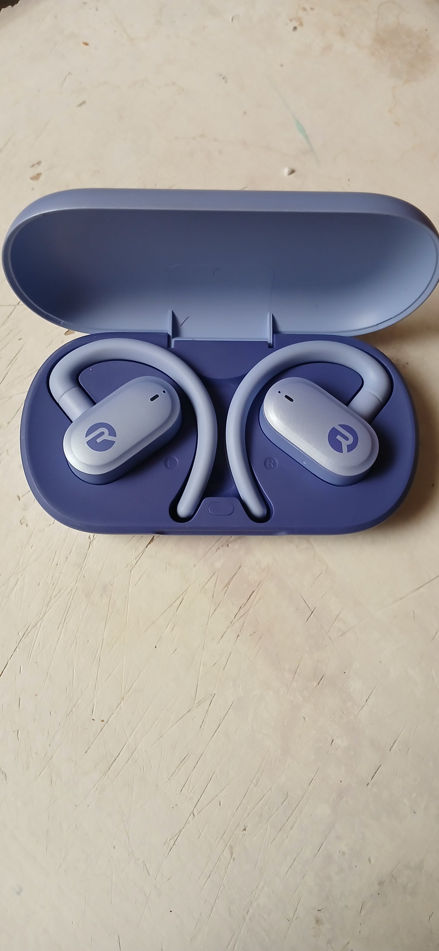 Wireless earbuds with charging case on a light wooden surface