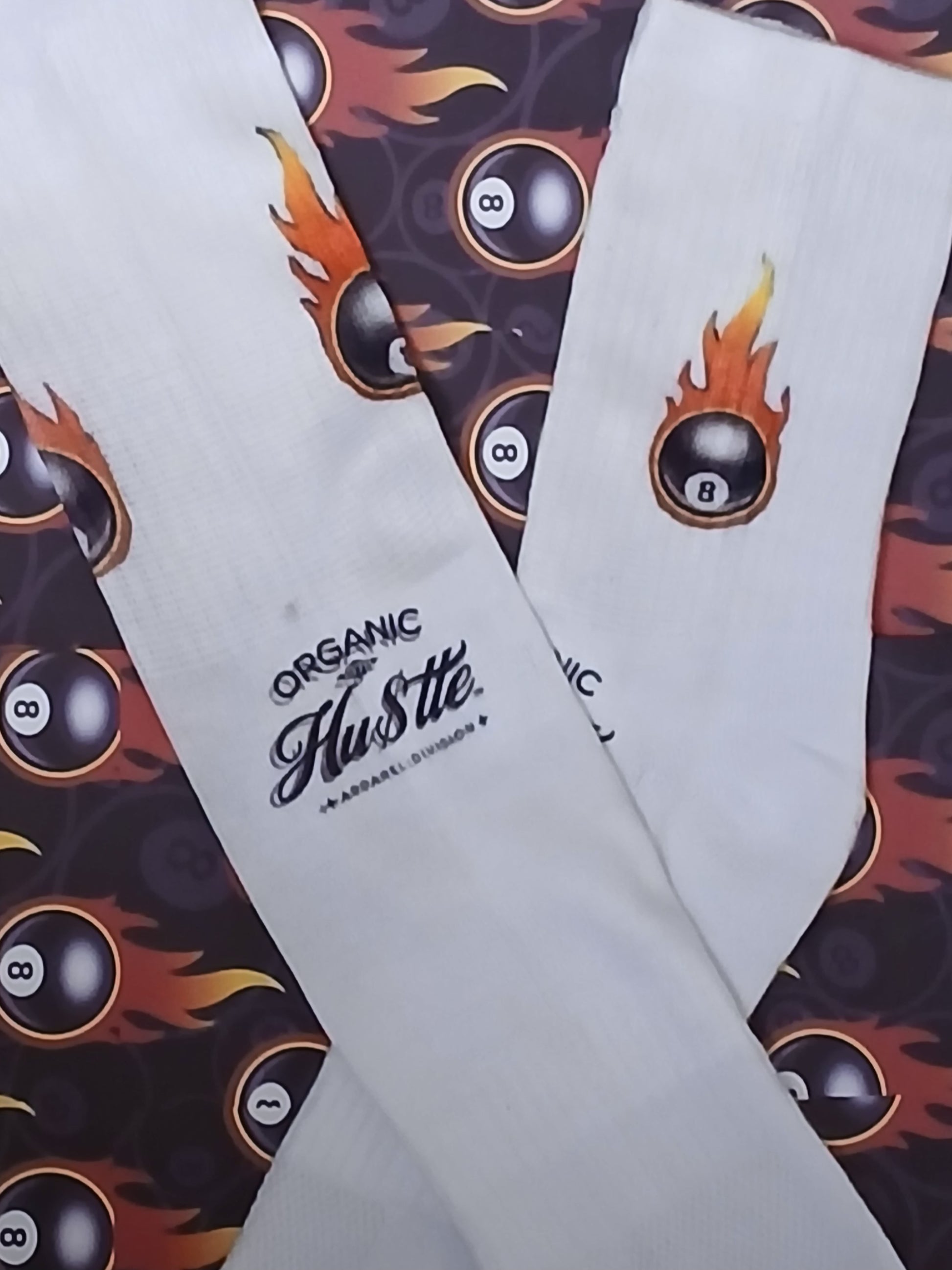 White socks with 'Organic Hustle' branding on a background with 8-ball design.