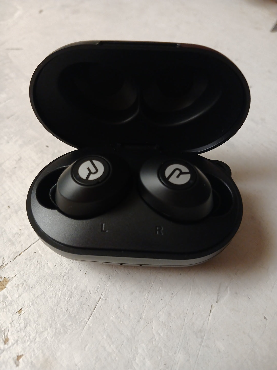 Black wireless earbuds in a charging case on a light surface